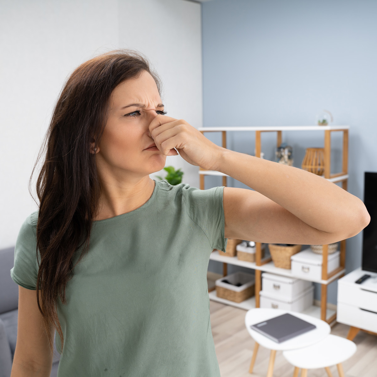 woman holding nose in smelly room
